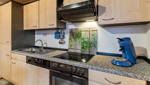 Una cocina con un lavaplatos doble, estufa y cafetera.