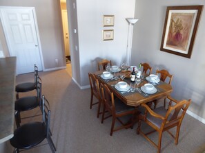 A dining room with a rectangular table set for six, surrounded by wooden chairs.