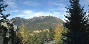 A mountain view with a building in the foreground and a fenced area with a pool.