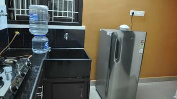 A kitchen with a water dispenser, a stove, and a refrigerator.