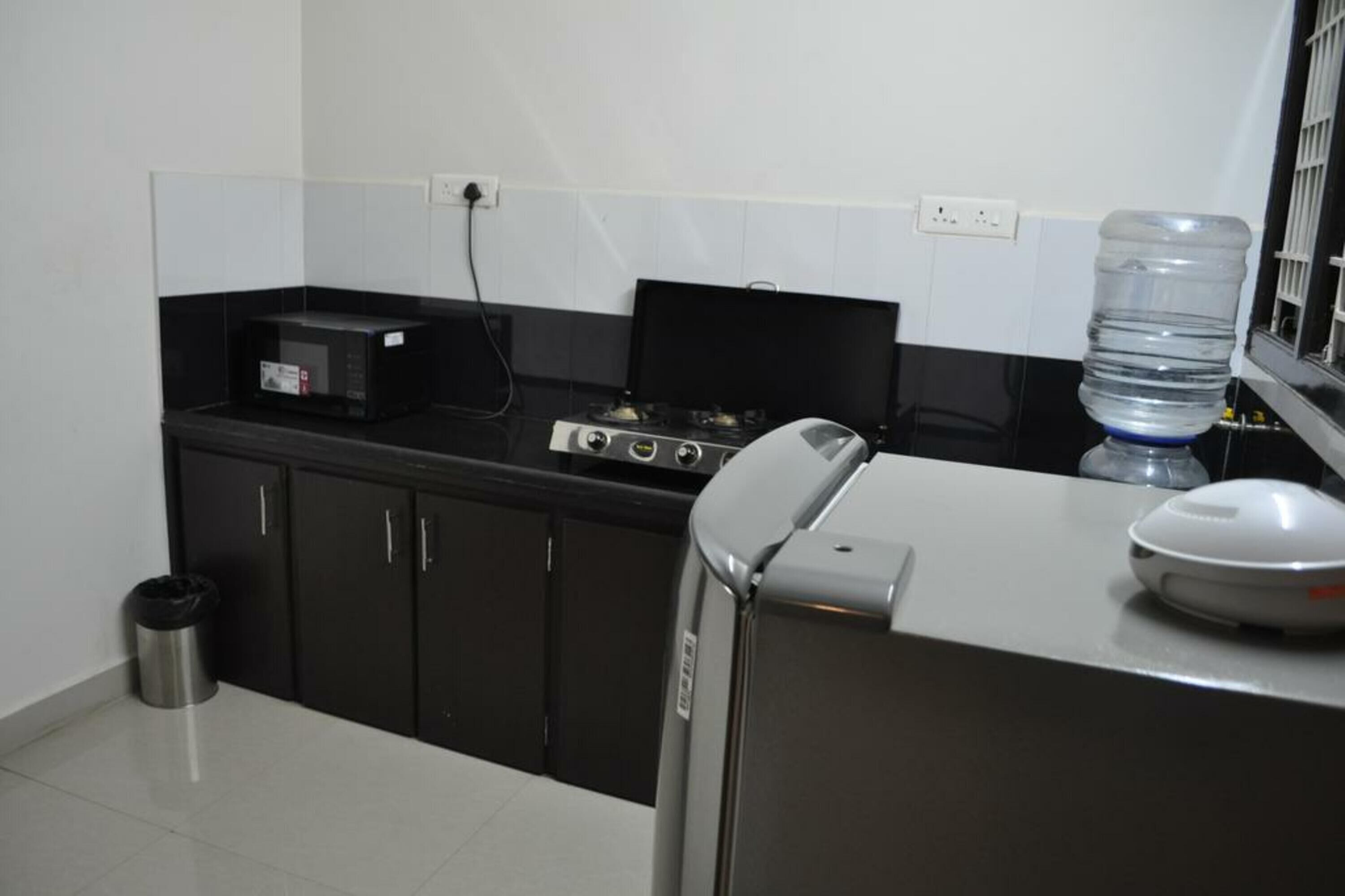 A kitchen with black cabinets, a gas stove, a microwave, and a water dispenser.