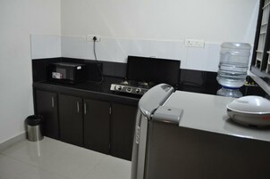Una cocina con armarios negros, estufa a gas, microondas y dispensador de agua.