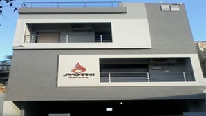 A modern building with a visible logo and a garage entrance. - Jyothi Suites (Tiruchirappalli)