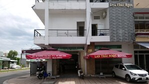 A hotel entrance with a red canopy and a white car parked in front. - Lan Thai Ngoc (Cao Lanh)