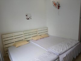Una cama individual con cabecera de madera, dos almohadas y una colcha blanca.
