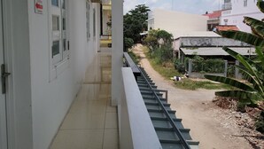 A corridor with a metal railing, a tiled floor, and a door with a sign. - Lan Thai Ngoc (Cao Lanh)