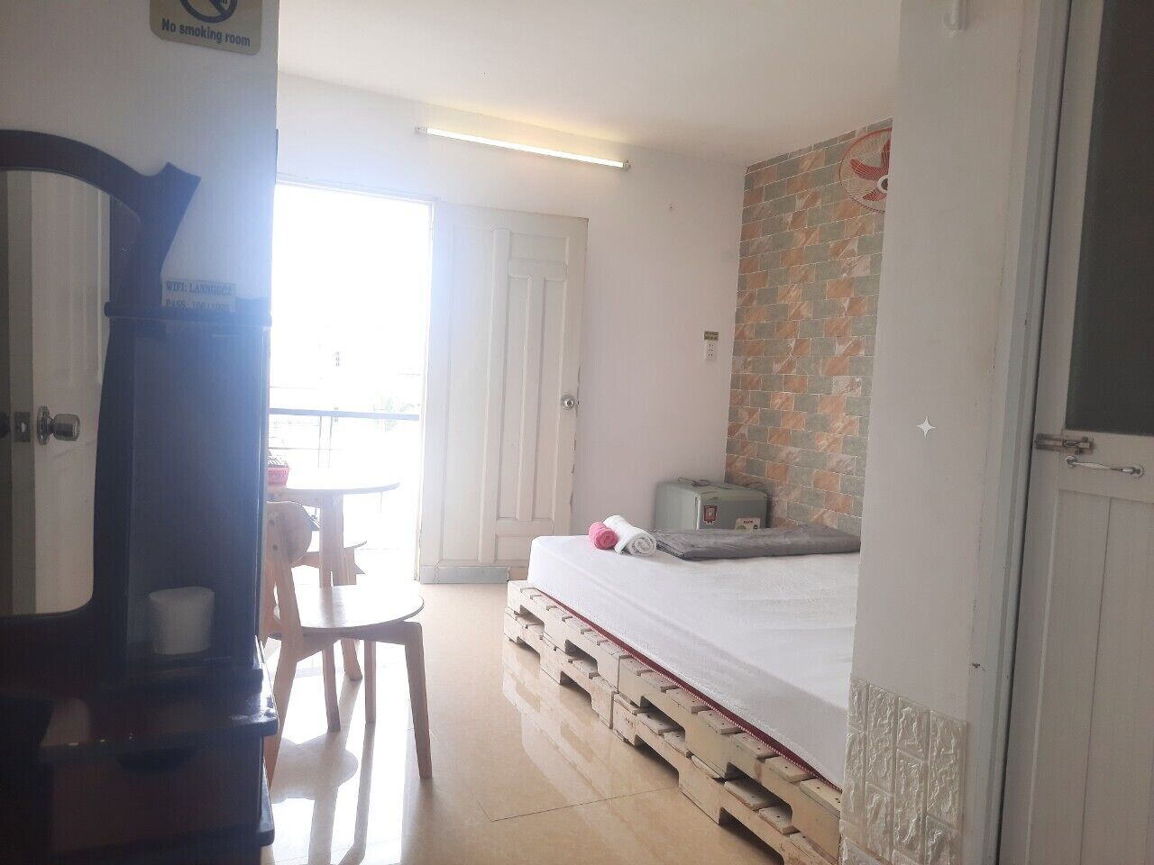 Una habitación con cama, una mesita, una silla y una maleta.