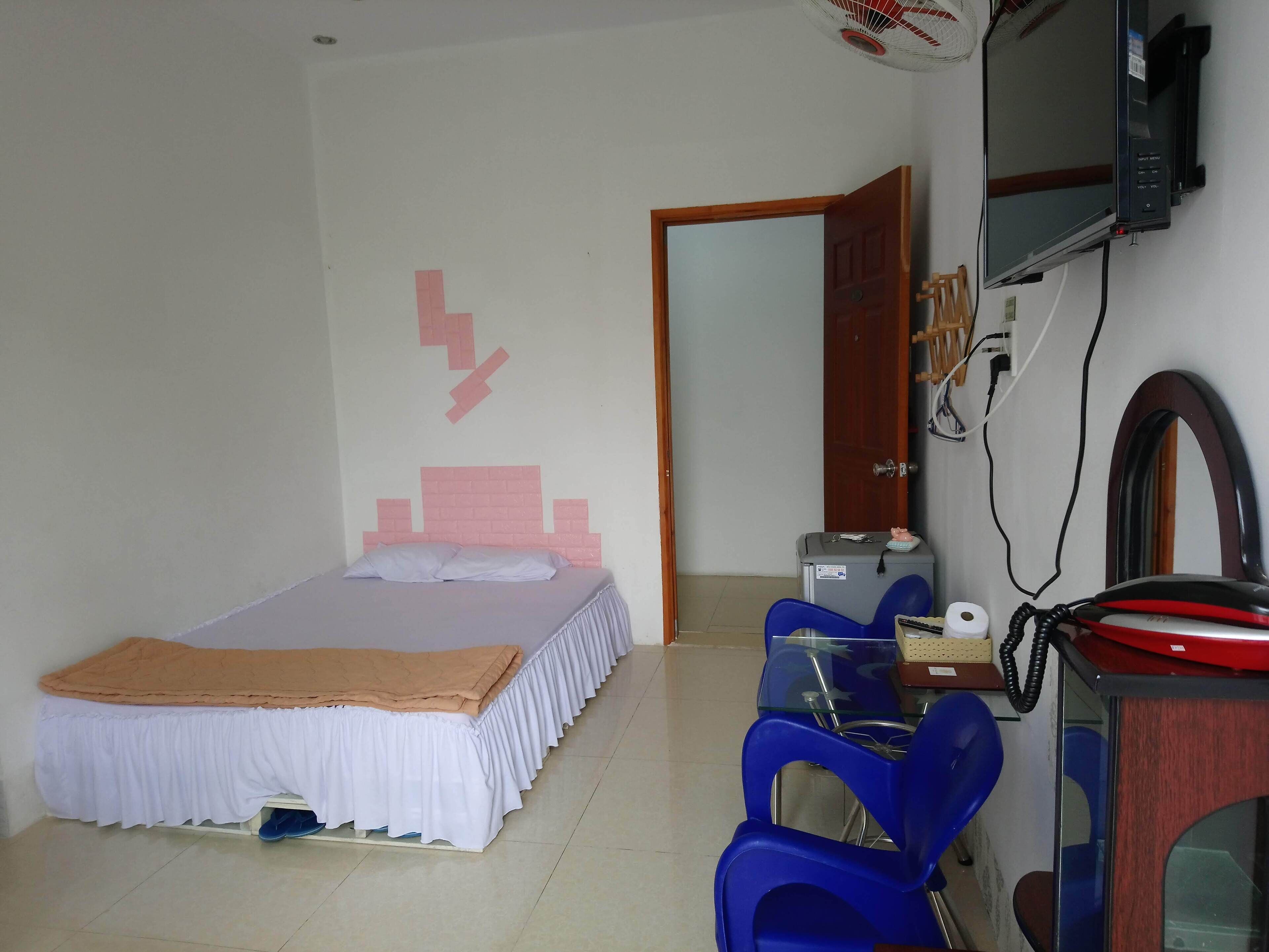 Ein Schlafzimmer mit einem Bett, einem Schreibtisch mit Stuhl, einem Fernseher und einem Telefon.