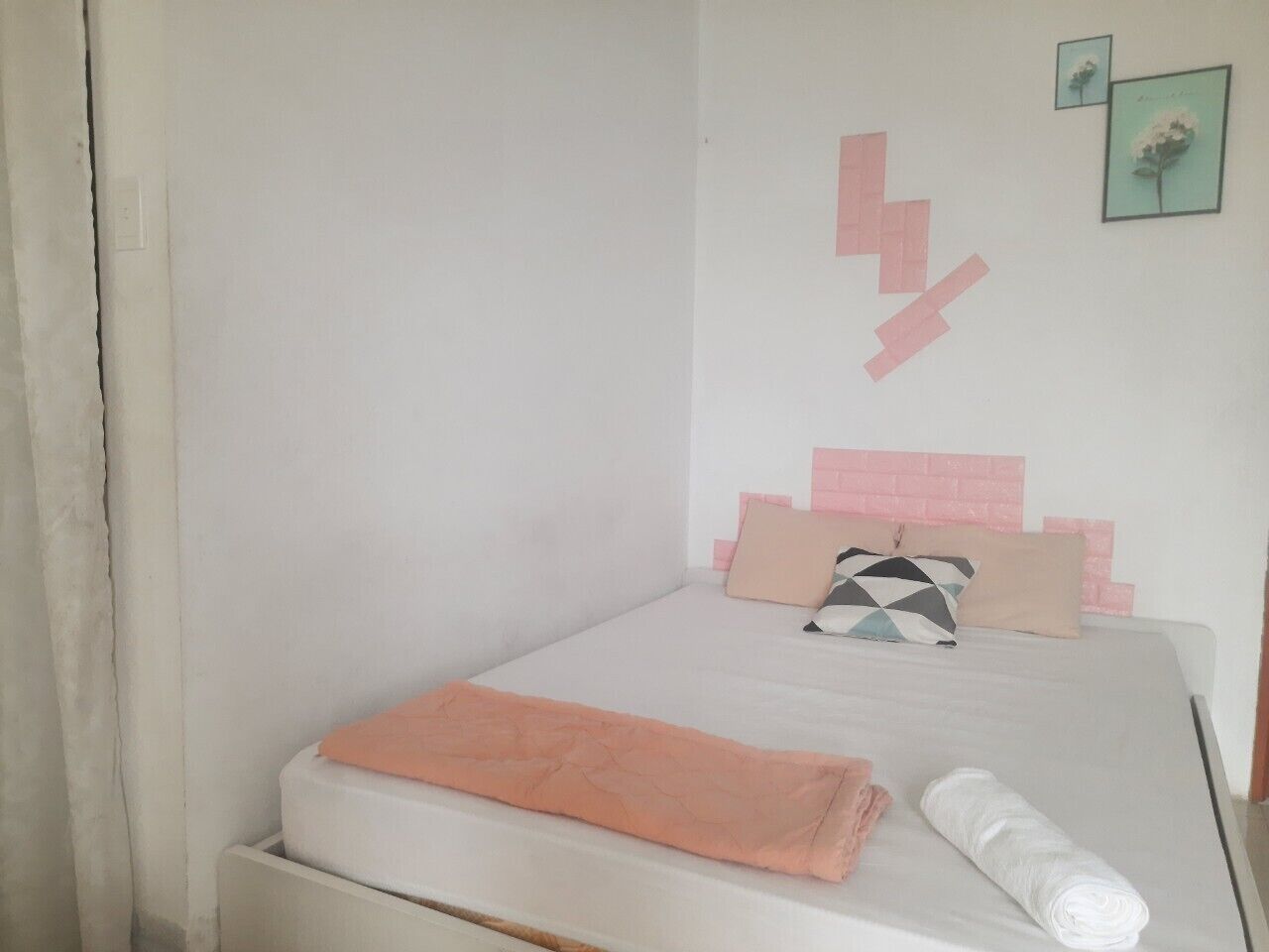 A small, neatly made bed with a white mattress and peach-colored bedding.