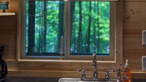 A kitchen with a window, a sink, and a light fixture above the window. -  Hocking Hills,Cozy Secluded Cabin,Minutes to Caves/WiFi/Pet Friendly! (McArthur)
