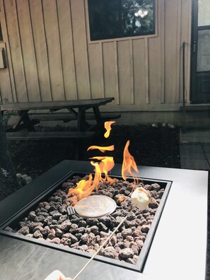 A square fire pit with burning charcoal and a metal plate, surrounded by rocks. - Mountain Retreat a property in the cool pines of Show Low, AZ.  (Show Low)