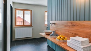 A bathroom with a wooden vanity, a bowl sink, a mirror, and a window.