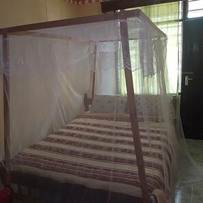 A room with a four-poster bed covered with a sheer canopy, a window with curtains, and a door. - Miritini guest house & restaurant (Mombasa)