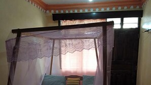 A single bed with a wooden frame and a mosquito net.