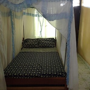 A bed with a canopy, patterned bedspread, and pillows. - Miritini guest house & restaurant (Mombasa)