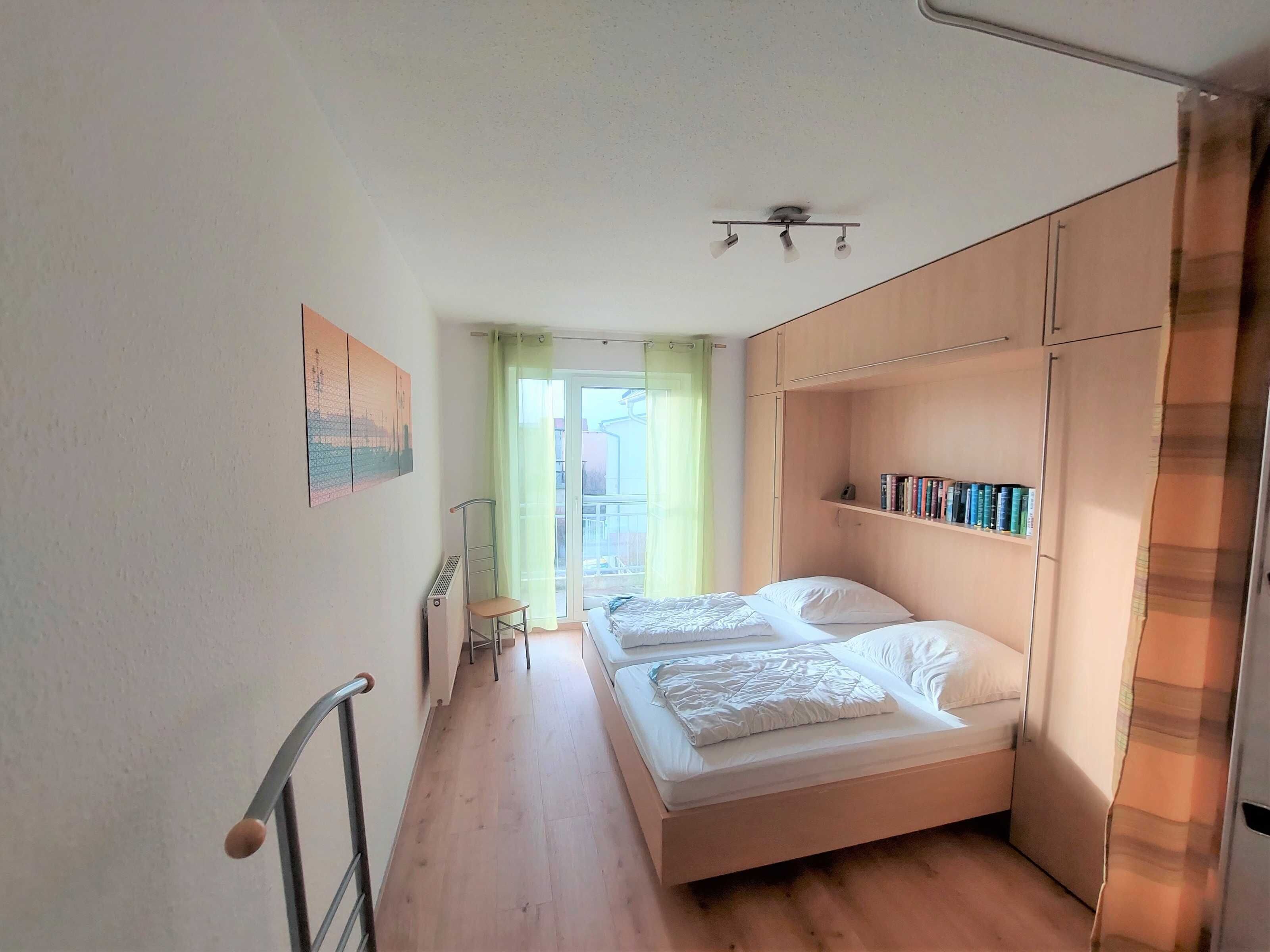 Un dormitorio con dos camas, un radiador, una silla y una estantería.
