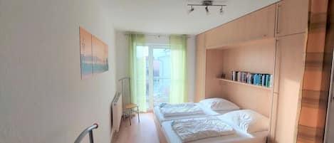 Un dormitorio con dos camas, un radiador, una silla y una estantería.
