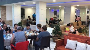 A dining area with tables and chairs, a sofa, and potted plants. - Palmiye Otel 2 (Erdemli)