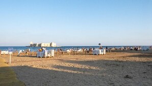 A beach with white tents and tables, a clear sky, and a historic building in the background. - Palmiye Otel 2 (Erdemli)