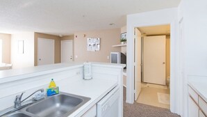 A compact kitchen with a double sink, a dishwasher, and a microwave. There is a small refrigerator and a cabinet above the sink. - Charmant Cosy et Design Vaucresson Séjour (Vaucresson)