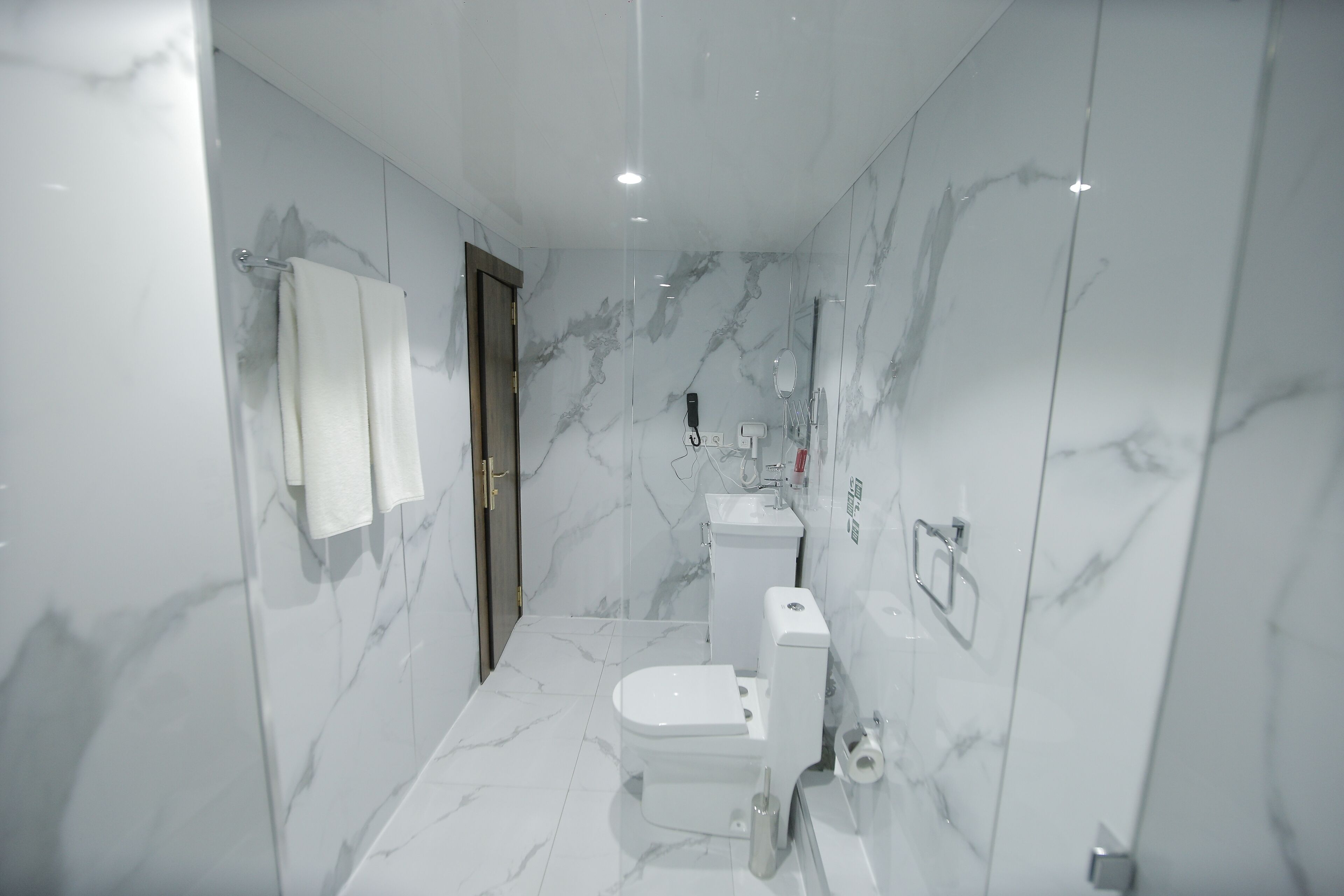 Een moderne badkamer met toilet, wastafel en spiegel.