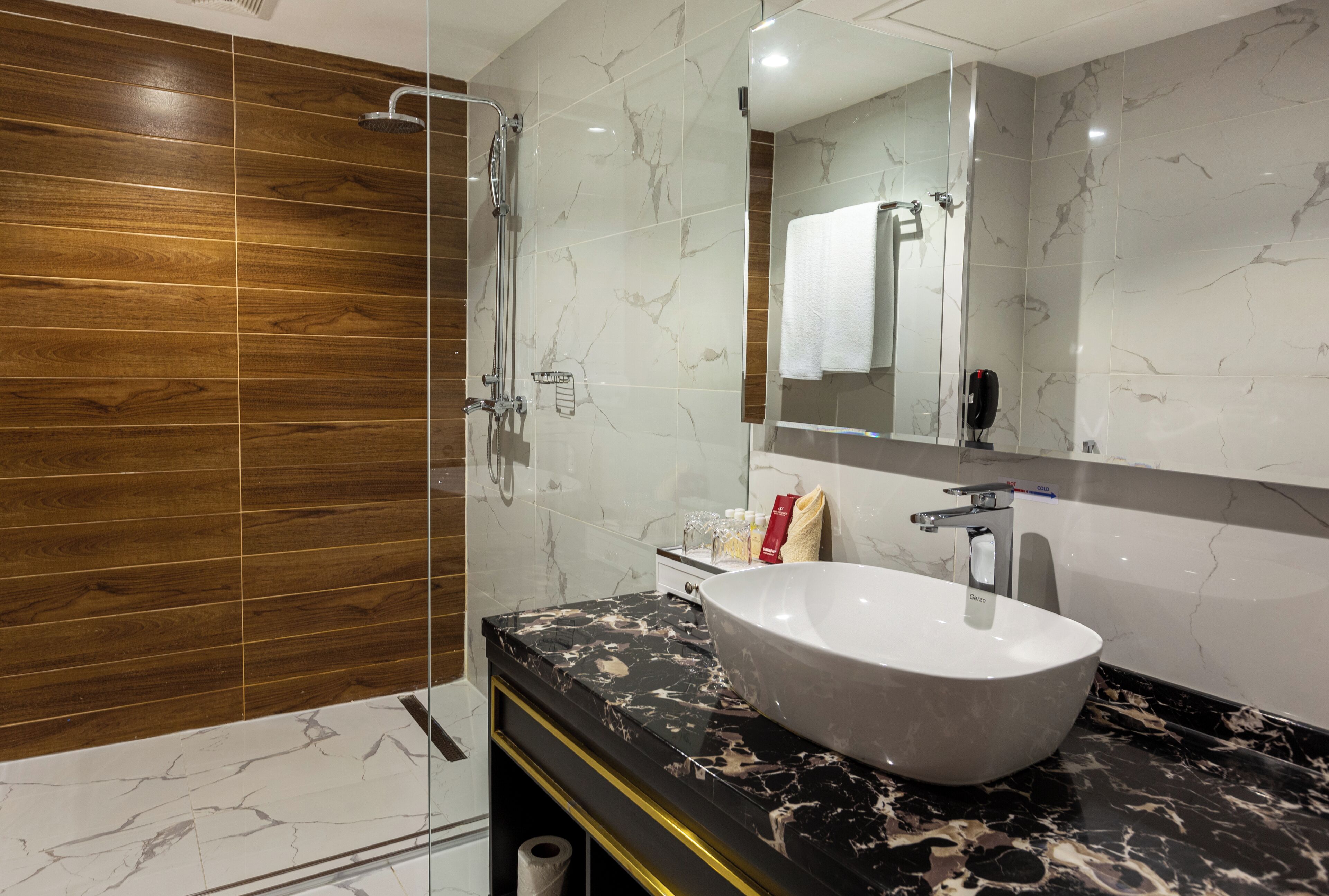 A modern bathroom with a large mirror, a white sink, and a shower area.