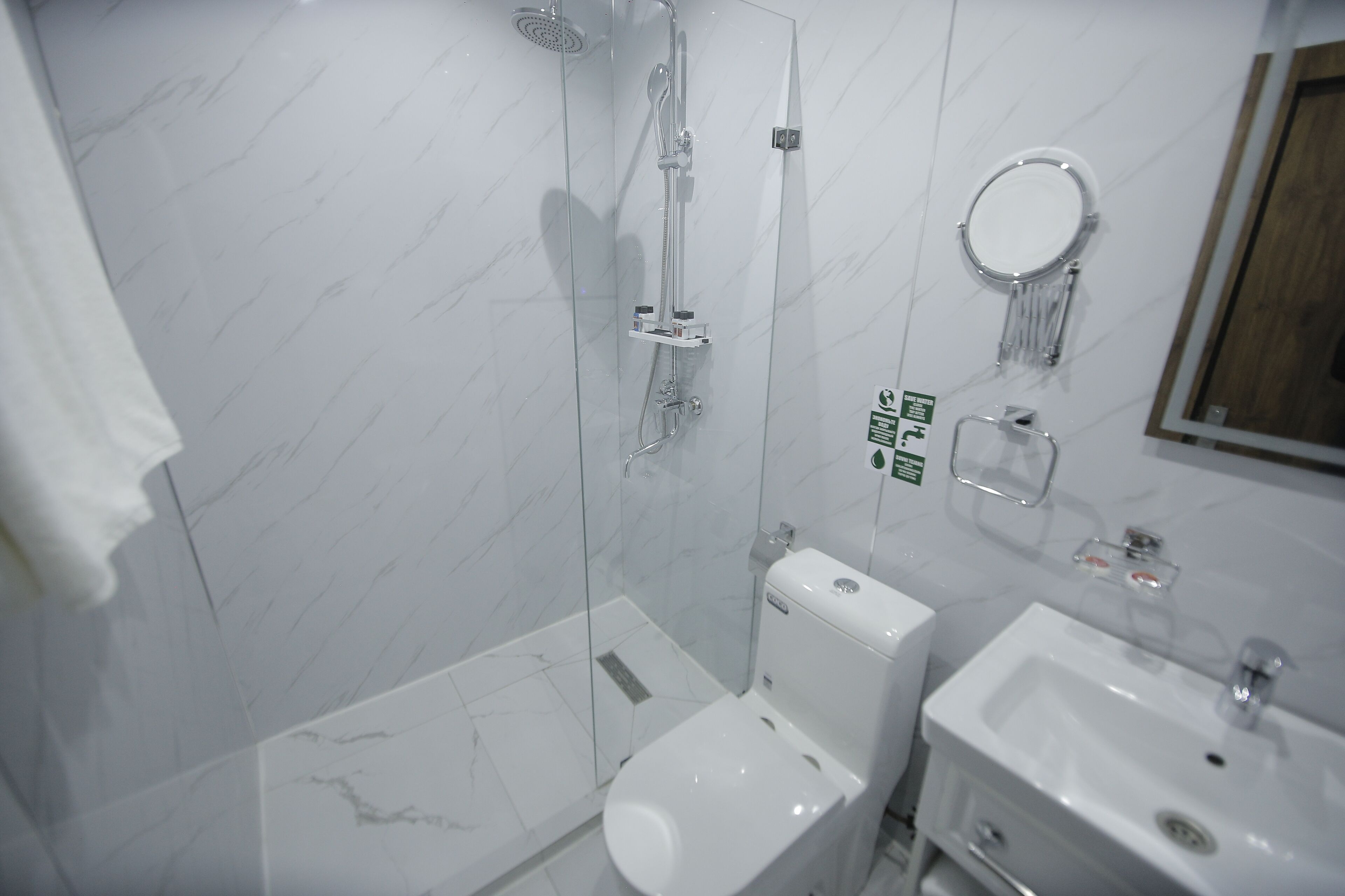Une salle de bain moderne dotée d’une douche à parois de verre, de toilettes et d’un lavabo.