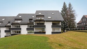 A modern multi-story residential building with a flat roof, large windows, and a grassy front yard. - Family & dog-friendly vacation apartment Hahnenklee with balcony near hiking trails (Goslar)