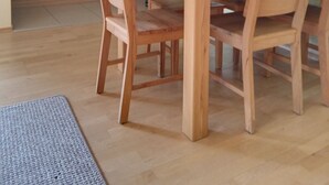 A dining area with a wooden table and chairs, a kitchen in the background, and a light green wall with picture frames. - Family & dog-friendly vacation apartment Hahnenklee with balcony near hiking trails (Goslar)