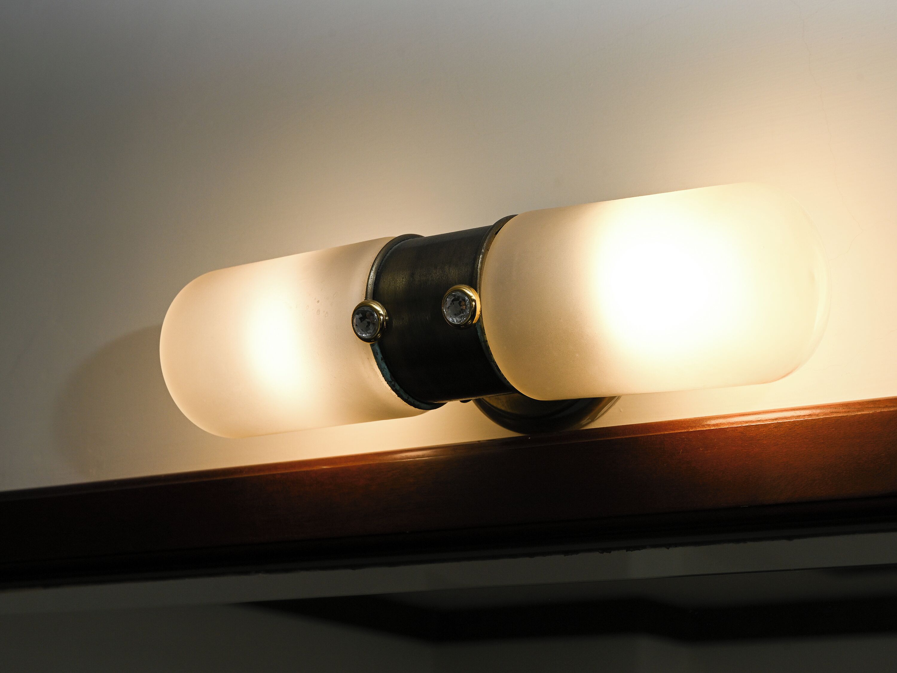 A wall-mounted light fixture with two frosted glass shades and a black metal base.
