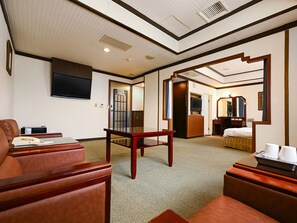 Une chambre dâhĂŽtel Ă©quipĂ©e dâun canapĂ©, dâun bureau, dâune tĂ©lĂ©vision, dâun miroir et dâune porte donnant sur une salle de bain.