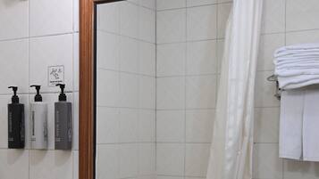 A bathroom with a large mirror, a sink, and three toiletries on the wall.