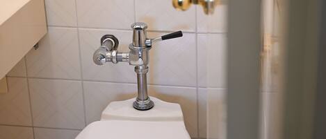 Un baño con un inodoro blanco, un grifo cromado y una cortina de ducha.