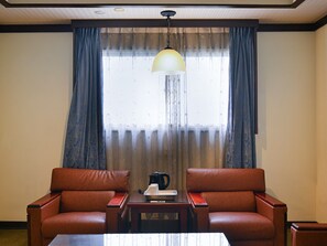 A room with two leather sofas, a wooden coffee table, and a hanging lamp. - Guide Hotel Chunghua Jhongjheng (Changhua)