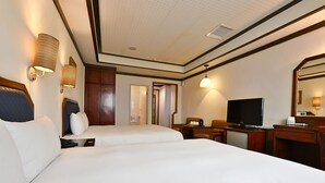 Habitación de hotel con dos camas, televisor, escritorio y espejo.