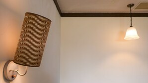 Una habitación con una lámpara de pared, una lámpara colgante y una mesa con cafetera y tazas.