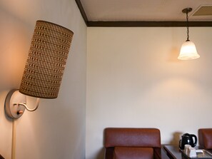 Ein Zimmer mit einer Wandlampe, einer Pendelleuchte und einem Tisch mit Kaffeemaschine und Tassen.