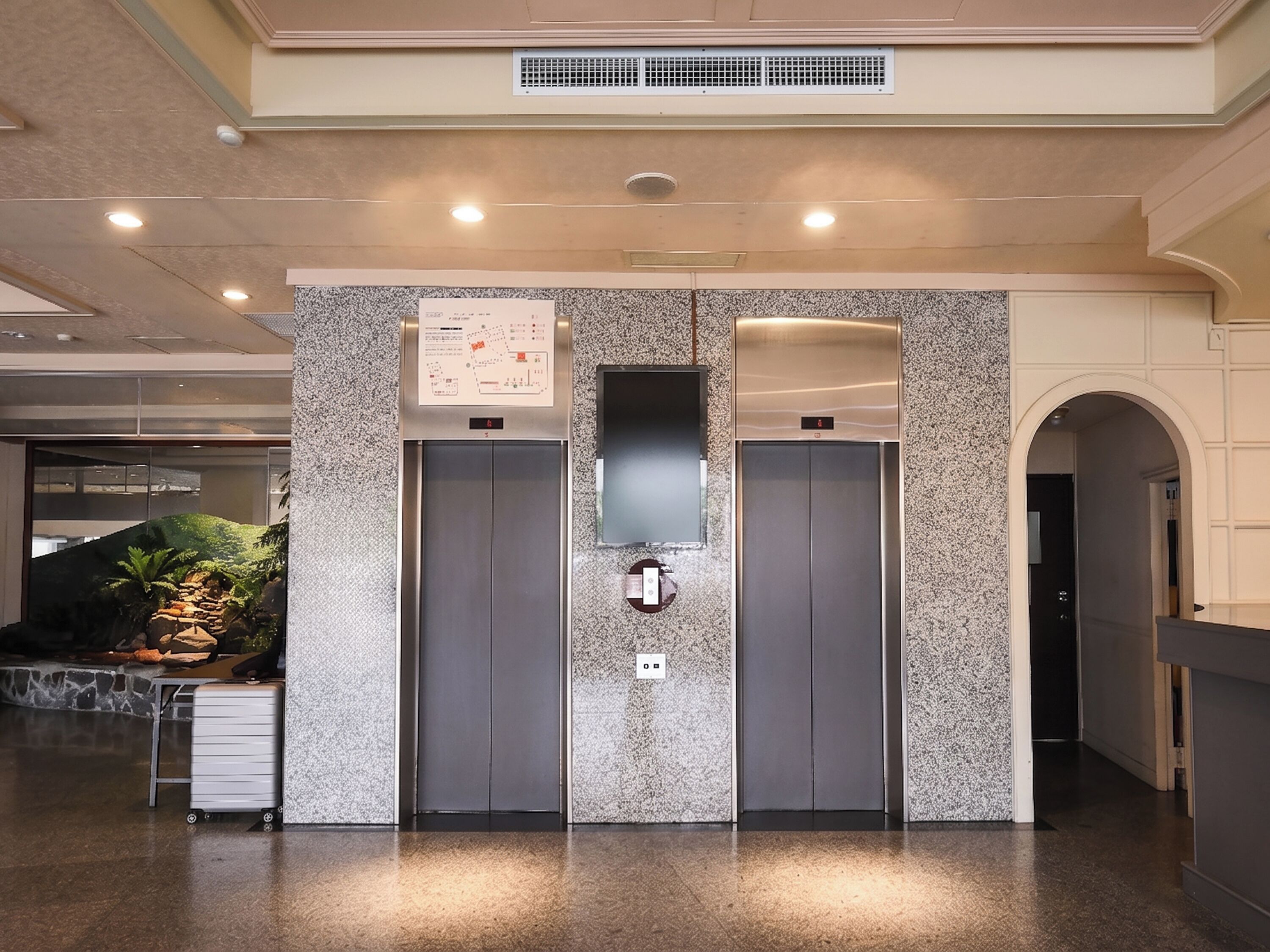 A modern elevator area with granite walls, a digital display, and a small plant.