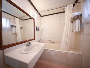 A bathroom with a sink, mirror, bathtub, and shower curtain. - Guide Hotel Chunghua Jhongjheng (Changhua)