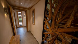 A hallway with a wooden bench, a wooden sculpture, and a door with a view of greenery. - NEW Garden 7 person Apartment with Hot Tub, next to Super Morzine (Morzine)