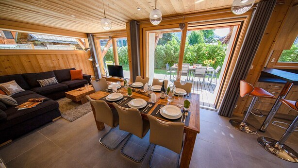 A dining area with a wooden table set for four, surrounded by chairs. - NEW Garden 7 person Apartment with Hot Tub, next to Super Morzine (Morzine)