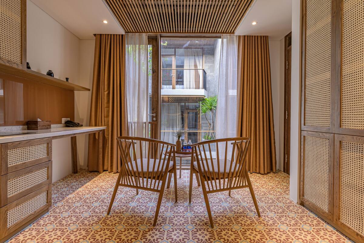 A room with a dining table, two chairs, a small plant, and a window with curtains.