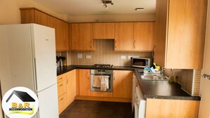 A compact kitchen with wooden cabinets, a white refrigerator, a stove, and a microwave. - ⭐B and R Serviced Accommodation and Apartments Amesbury⭐ Archer house  (Amesbury)