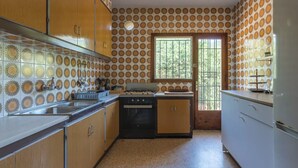 Una cocina con armarios de madera, estufa y ventana con vistas al verdor.