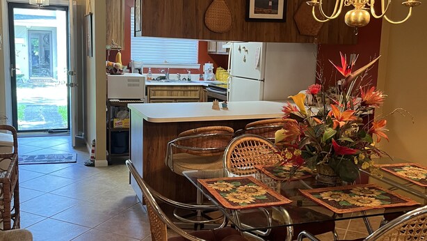 A modern kitchen with wooden cabinets, a dining table with chairs, a chandelier, and a view of the backyard. - Spacious quiet 3BR townhome Five minutes to beach (St. Simons Island)