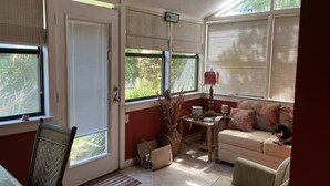 A sunlit room with a sofa, a table, and a chair. - Spacious quiet 3BR townhome Five minutes to beach (St. Simons Island)