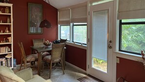A room with a dining table, chairs, a bookshelf, and a large window with blinds. - Spacious quiet 3BR townhome Five minutes to beach (St. Simons Island)