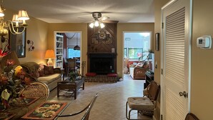 A living room with a fireplace, a dining table with chairs, a sofa, and a chandelier. - Spacious quiet 3BR townhome Five minutes to beach (St. Simons Island)
