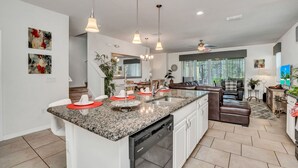 A spacious kitchen with granite countertops, a dishwasher, and pendant lighting.