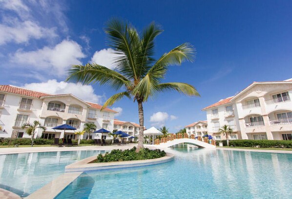 A resort with a swimming pool, palm trees, and white buildings with balconies. - The emerald oasis of the caribbean , at the heart of the universe (Bayahibe Dominicus)